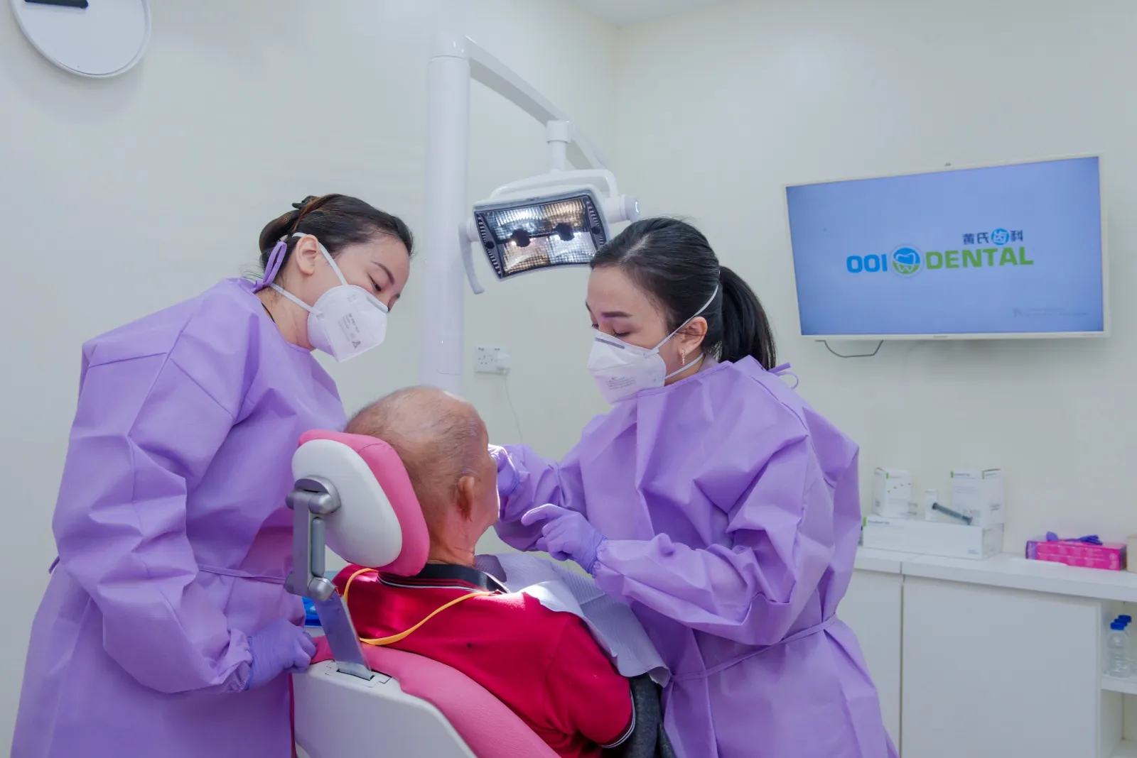 Two Ooi Dental dentists with a patient in the treatment chair