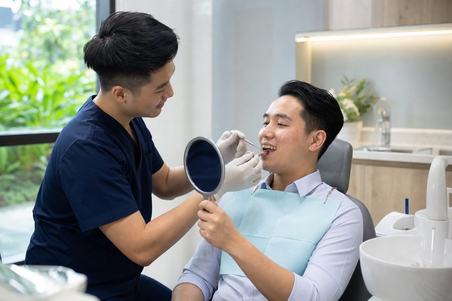 A dentist checking a patient's teeth at a routine review